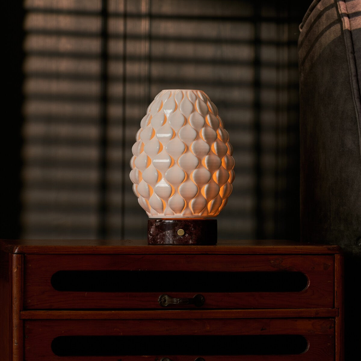 Serena Rosso Levanto rechargeable table lamp lit beside framed art on a dark wooden sideboard
