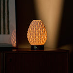 Serena Rosso Levanto cordless table lamp glowing on a cabinet beneath green striped wall art