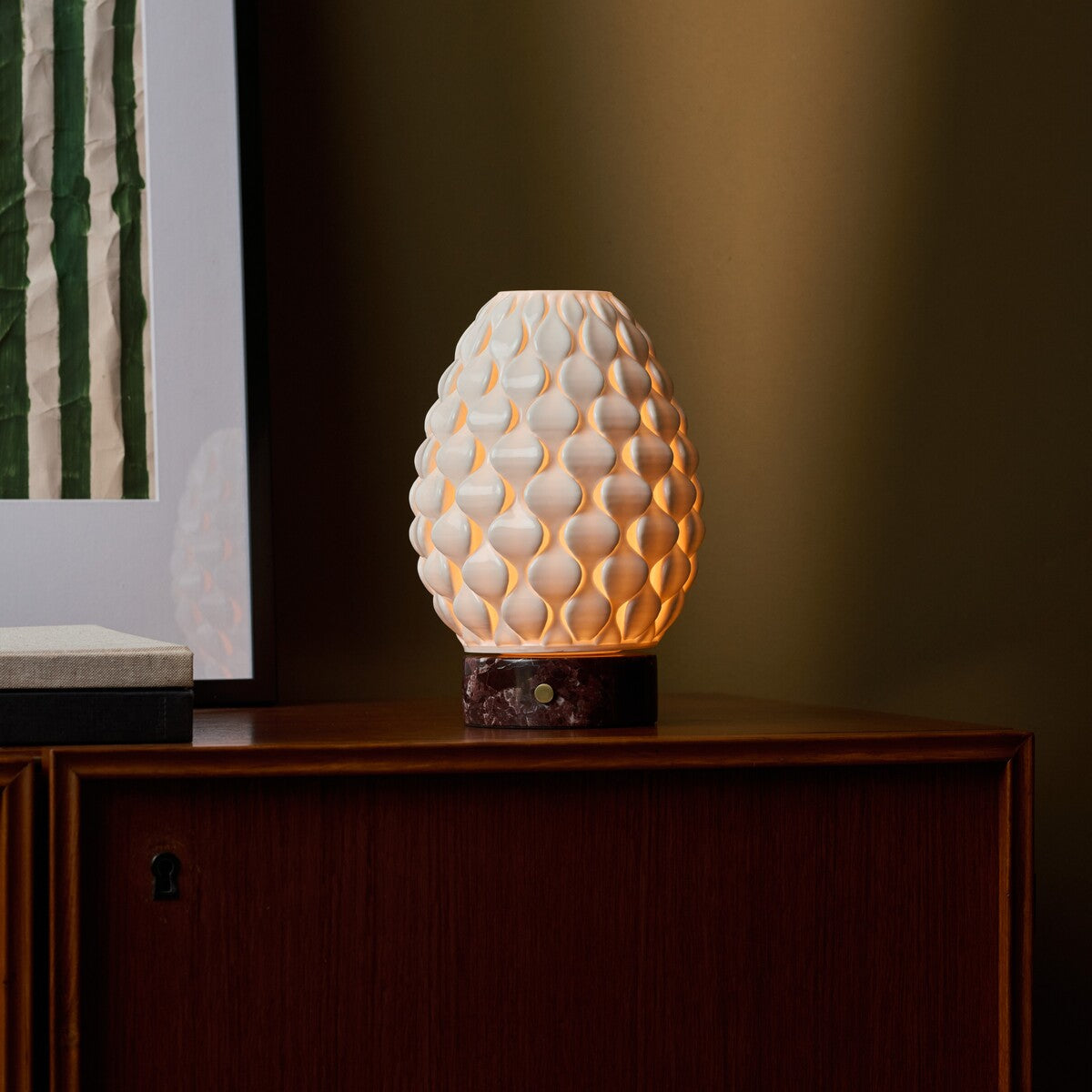 Close-up of the Serena Rosso Levanto rechargeable table lamp's red marble base held on someone's lap