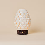 Serena Rosso Levanto cordless table lamp glowing on a dark wood dresser in a striped-blind bedroom