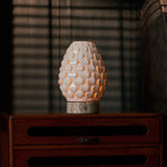 Cordless table lamp Serena silver travertine porcelain shade glowing on wooden cabinet
