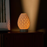 Cordless table lamp Serena silver travertine porcelain shade glowing warm against brown wall