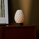 Serena Verde Alpi cordless table lamp glowing on a cabinet beneath green striped wall art