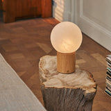 Flore oplaadbare tafellamp met lichtbruin houten voet op een rustieke houten boomstronk