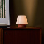 Oplaadbare tafellamp Hooch Small met rode Travertine marmeren voet tegen olijfgroene muur