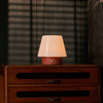 Oplaadbare tafellamp Hooch Small met rode Travertine voet, brandend op houten dressoir