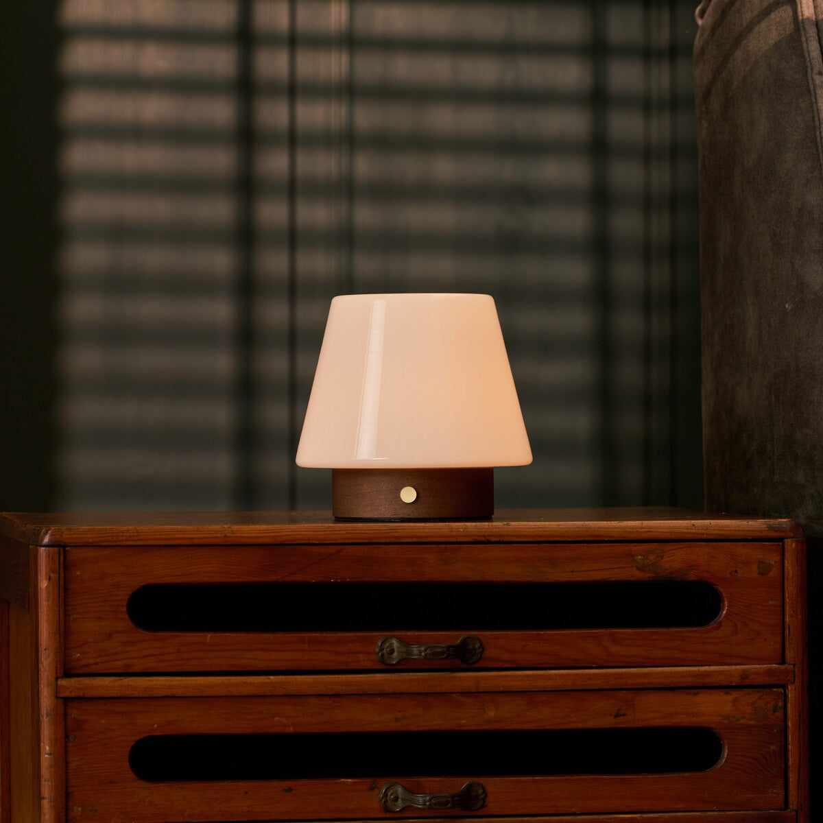 Oplaadbare tafellamp Jadey donkerbruin hout brandend op een houten dressoir 's avonds