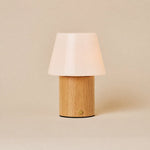Rechargeable table lamp Jadey Medium, light wood base with white glass shade on beige studio background