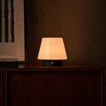 Oplaadbare tafellamp Jadey zwarte houten voet en opaline kap brandend op houten dressoir