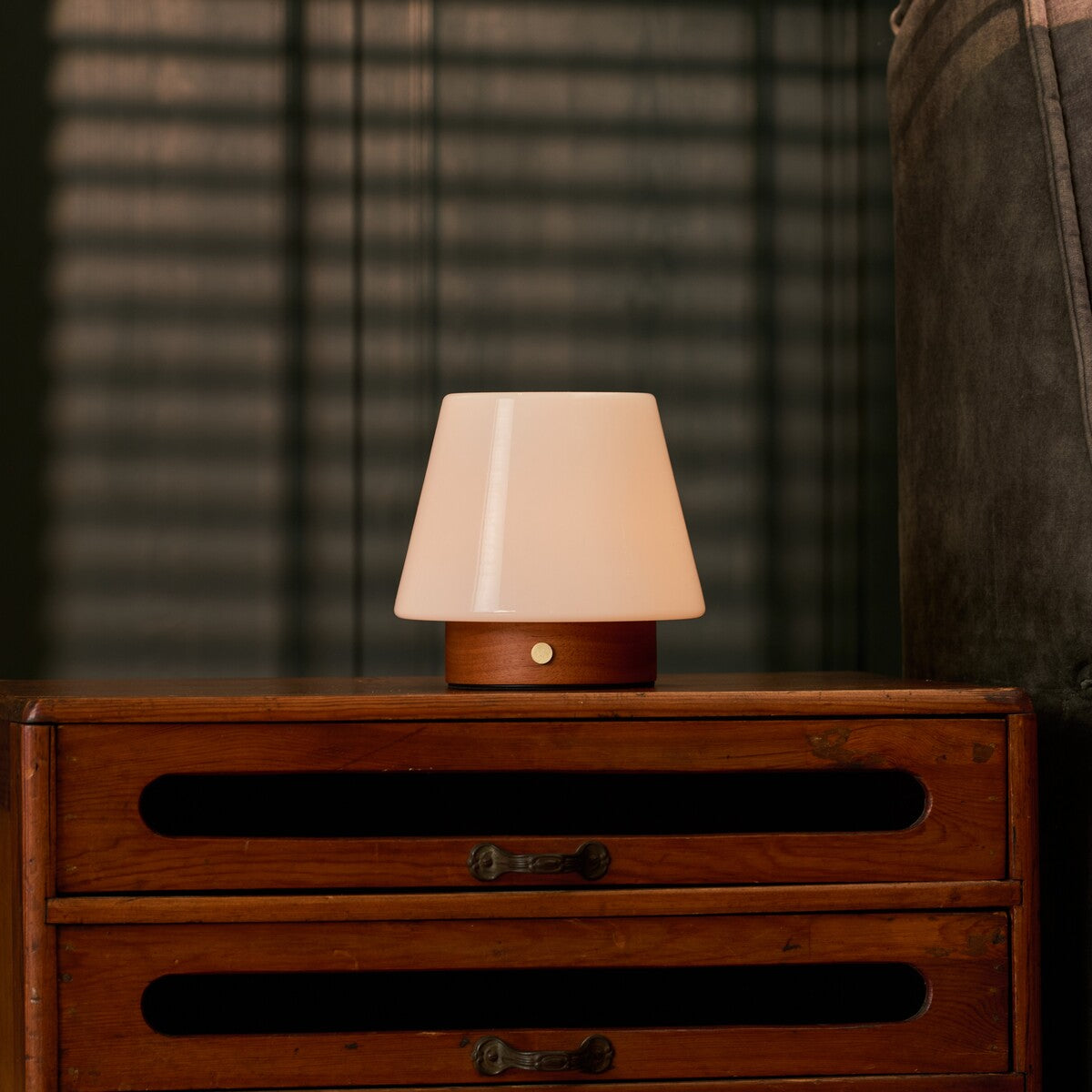 Tafellamp oplaadbaar Jadey Small kastanjebruin hout, zacht gloeiend op houten dressoir in slaapkamer