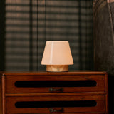 Oplaadbare tafellamp Jadey Small, hout met glazen kap brandend op donkere houten ladekast