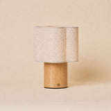 Lucy bois clair lampe de table sans fil Tavellio – abat-jour ondulé en lin naturel – sur fond beige en studio