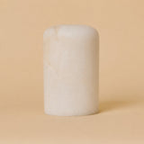 Rechargeable table lamp Tavellio Noé alabaster shade shown on its own, rounded cylinder against an ochre backdrop.