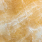 Close-up of raw Honey Onyx marble showing warm gold and cream veining used for the lamp base