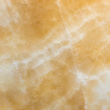 Close-up of raw Honey Onyx marble showing warm gold and cream veining used for the lamp base
