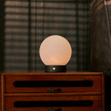 Oplaadbare tafellamp Flore Small zwart hout met glazen bol op slaapkamerdressoir