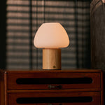 Fynn rechargeable table lamp with light brown wood cylinder base on dark wooden dresser